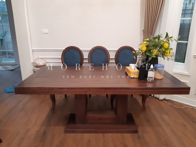 Thi công một bàn ăn hình chữ nhật có chân trụ giữa và diện tích bề mặt rộng rãi, 4 góc vuông tạo sự vuông vắn phù hợp với nhu cầu của gia đình có nhiều thành viên và có trẻ nhỏ. Bàn ăn được làm bằng gỗ tự nhiên.
